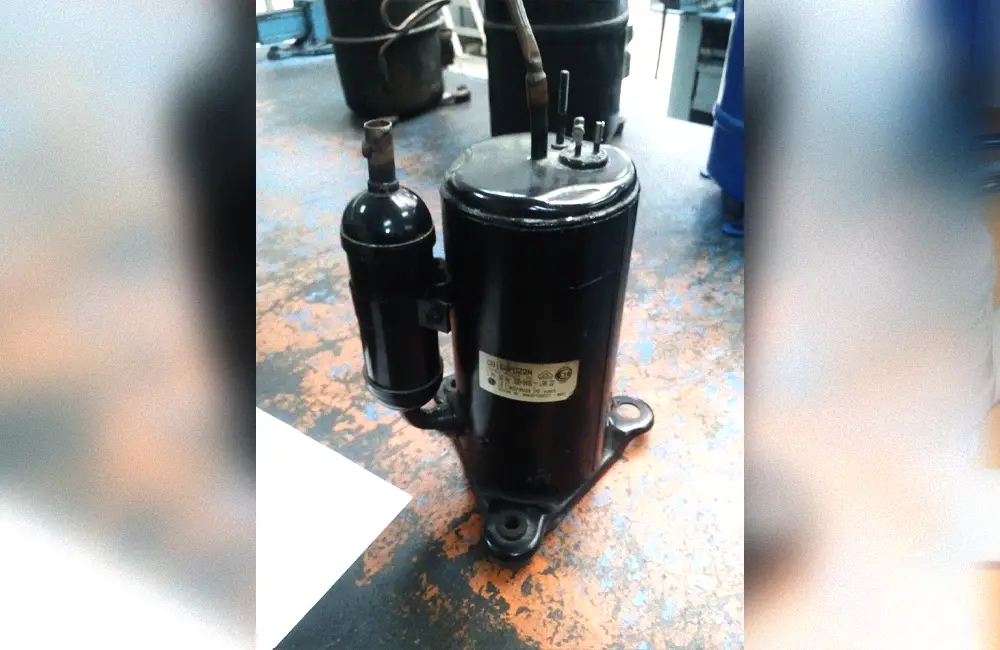 Disassembled hermetic rotary compressor showing its housing and internal mechanism